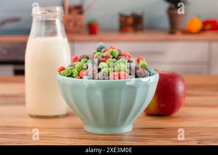 Schüssel mit roten, violetten und blauen Beeren gewürzten Kindermüsli auf einem hölzernen Küchentisch Stockfoto