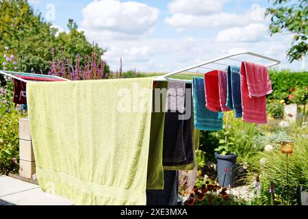 Wäschetrockner steht auf der Terrasse an sonnigen Tagen zum Trocknen mehrfarbiger Handtücher. Zusammenklappbare Kleidung Stockfoto