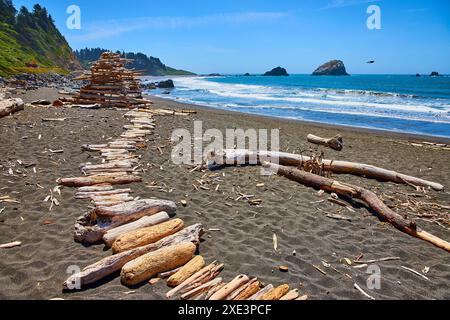 Driftwood Pyramid Art am sonnigen DeMartin Beach mit Küstenlandschaft Stockfoto