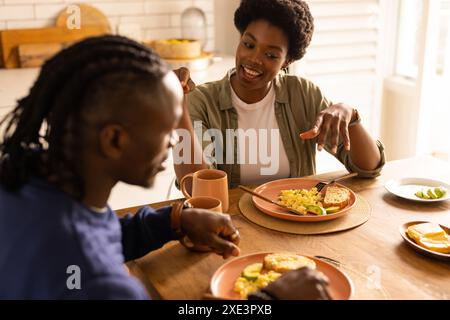 Ein Paar genießt das Frühstück zu Hause, lächelt und unterhält sich Stockfoto