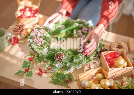 Frau, die Mistelkranz macht Weihnachtskranz Dekoration mit handgemachten DIY Winter Grün Blumenhändler Hände machen Weihnachtswrea Stockfoto