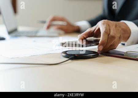 Laden des Mobiltelefonakkus mit drahtlosem Ladegerät im Tisch. Smartphone wird auf einem Ladepad aufgeladen. Mobiltelefon ne Stockfoto