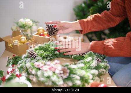 Frau, die Mistelkranz macht Weihnachtskranz Dekoration mit handgemachten DIY Winter Grün Blumenhändler Hände machen Weihnachtswrea Stockfoto