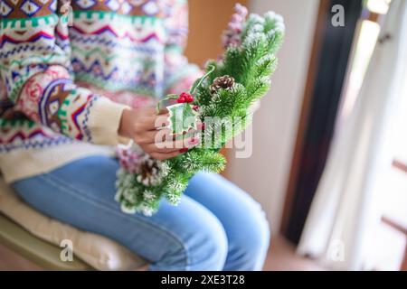 Frau, die Mistelkranz macht Weihnachtskranz Dekoration mit handgemachten DIY Winter Grün Blumenhändler Hände machen Weihnachtswrea Stockfoto