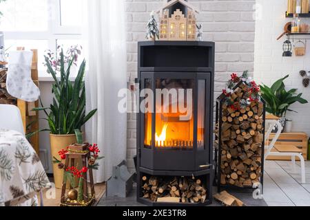 Schwarzer Metallofen, brennender Kamin im weißen festlichen Innenraum des Hauses ist für Weihnachten und Neujahr, Christm dekoriert Stockfoto