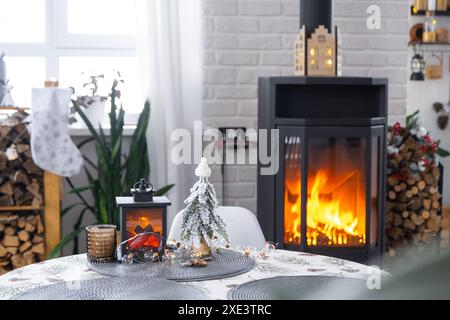 Schwarzer Metallofen, brennender Kamin im weißen festlichen Innenraum des Hauses ist für Weihnachten und Neujahr, Christm dekoriert Stockfoto