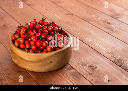 Rote Hagebuttenfrüchte in einer Holzschale auf Holztisch Stockfoto