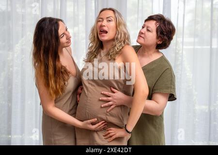 Porträt einer schwangeren Frau mit Mutter und Schwester am Fenster Stockfoto