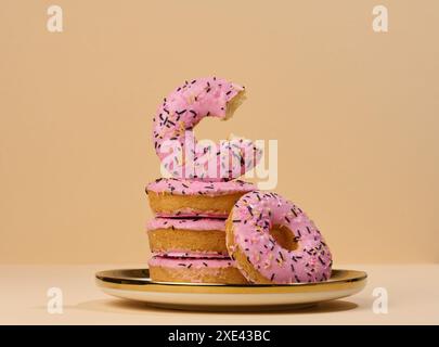 Donut bedeckt mit rosafarbener Glasur und mit bunten Streuseln auf einem runden Teller bestreut Stockfoto