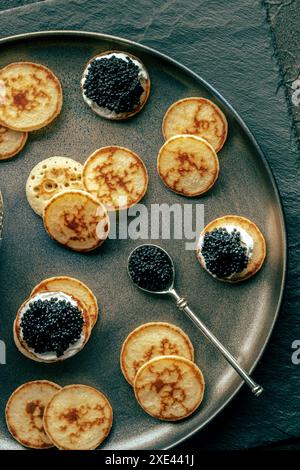 Blinis mit schwarzem Kaviar und Frischkäse, von oben geschossen, Mini-Pfannkuchen Stockfoto