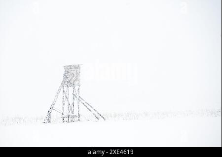 Jagdturm auf dem Land während des Schneesturms. Schneebedeckter Jagdaussichtspunkt auf dem Feld im Winter. Stockfoto