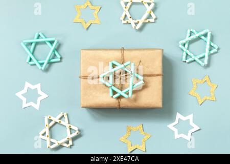 Jüdischer Feiertag Chanukka. Ein Geschenk und Symbol des Chanukka-Sterns von David auf blauem Hintergrund. Draufsicht flach liegend. Stockfoto