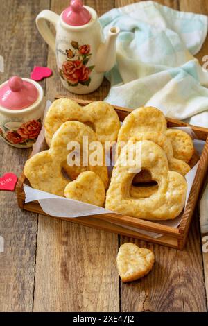 Valentinstag, Geburtstag oder Muttertag, Frühstück, Weihnachtsessen. Hausgemachte Quark-Kekse mit Herzen auf einem rustikalen Holzkekse Stockfoto