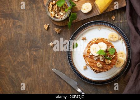 Pancake Day, amerikanisches Frühstück. Köstliche hausgemachte Bananenpfannkuchen mit Nüssen und Karamell auf rustikalem Holztisch. Bis Stockfoto