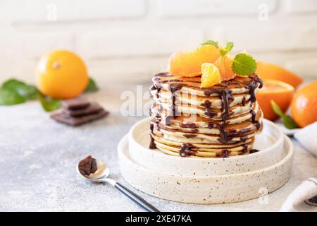 Pancake Day feiern, gesundes Frühstück. Köstliche hausgemachte amerikanische Bananenpfannkuchen mit Schokolade und roter Orange auf grauen s Stockfoto