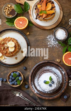Pancake Day feiern, gesundes Frühstück. Köstliche hausgemachte amerikanische Bananenpfannkuchen mit Heidelbeeren, Nüssen, Karamell, Chocolo Stockfoto