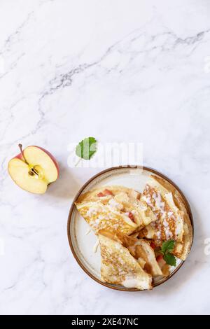 Pancake Day feiern, gesundes Frühstück. Hausgemachte süße Crepes mit Äpfeln und Kondensmilch auf einer Marmorplatte. Draufsicht Stockfoto