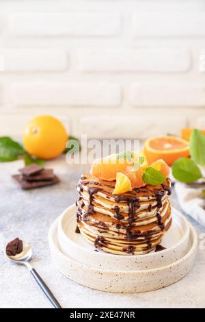 Pancake Day feiern, gesundes Frühstück. Köstliche hausgemachte amerikanische Bananenpfannkuchen mit Schokolade und roter Orange auf grauen s Stockfoto