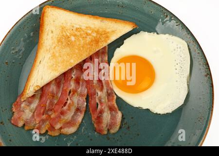 Schließen Sie Ei, Toast und Speck auf blauem Teller Stockfoto