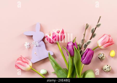 Osterkomposition mit bunten Ostereiern und Frühlingsblumen Tulpen auf rosa Hintergrund. Frühjahrs- und Osterferienkonzept. Stockfoto