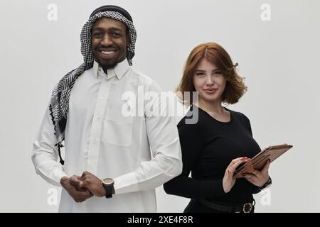 Eine arabische Unternehmerin und eine Geschäftsfrau, die Vertrauen und Einheit ausstrahlt, posieren zusammen vor einem sauberen weißen Hintergrund und symbolisieren Stockfoto