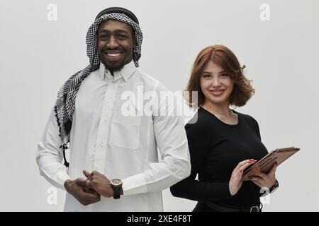 Eine arabische Unternehmerin und eine Geschäftsfrau, die Vertrauen und Einheit ausstrahlt, posieren vor einem klaren weißen Hintergrund und symbolisieren eine dynamische Partnerschaft Stockfoto
