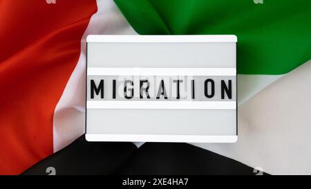 NACHRICHTENMIGRATION auf Hintergrund der Flagge der VAE aus Seide. Nationalflagge der Vereinigten Arabischen Emirate mit Konzept für Tourismus und trave Stockfoto