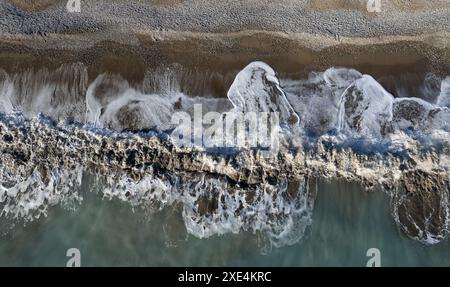 Aus der Vogelperspektive auf stürmische Meereswellen, die an einem Strand brechen. Naturhintergrund Stockfoto