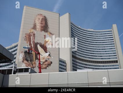Wien, Österreich. Juni 2024. Der australische Künstler Fintan Magee (l auf dem Kran) malt eine weibliche Figur mit einer Taube auf einer Wand des Vienna International Center (VIC) in luftiger Höhe. In Zusammenarbeit mit dem Wiener Kulturverein Calle Libre, den UN-Organisationen in Wien und weiteren Projektpartnern entsteht Wiens größtes Wandbild. Sie dient der Unterstützung der Nachhaltigkeitsziele und des künftigen UN-Gipfels im September. Frank Rumpenhorst/dpa/Alamy Live News Stockfoto