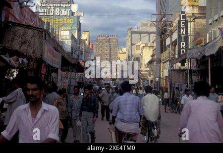 Menschen in einer Straße mit Blick auf den Turm des Meenakshi Amman Tempels in der Stadt Madurai in der Provinz Tamil Nadu in Indien. Indien, Madurai, Stockfoto