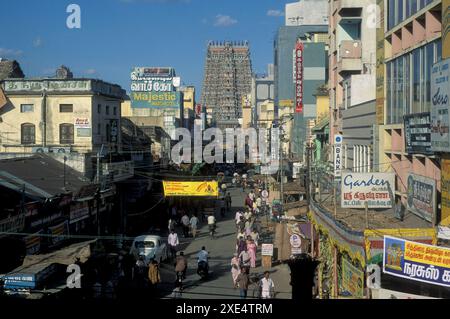 Menschen in einer Straße mit Blick auf den Turm des Meenakshi Amman Tempels in der Stadt Madurai in der Provinz Tamil Nadu in Indien. Indien, Madurai, Stockfoto