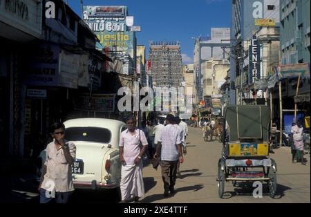 Menschen in einer Straße mit Blick auf den Turm des Meenakshi Amman Tempels in der Stadt Madurai in der Provinz Tamil Nadu in Indien. Indien, Madurai, Stockfoto