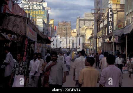 Menschen in einer Straße mit Blick auf den Turm des Meenakshi Amman Tempels in der Stadt Madurai in der Provinz Tamil Nadu in Indien. Indien, Madurai, Stockfoto