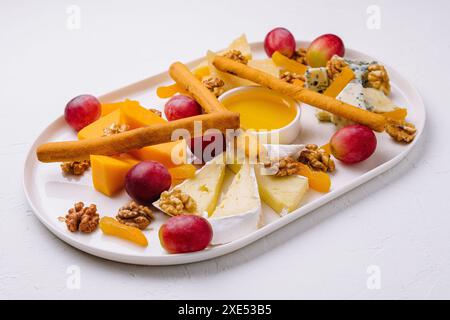 Käseplatte mit Honig, Nüssen und roten Trauben Stockfoto