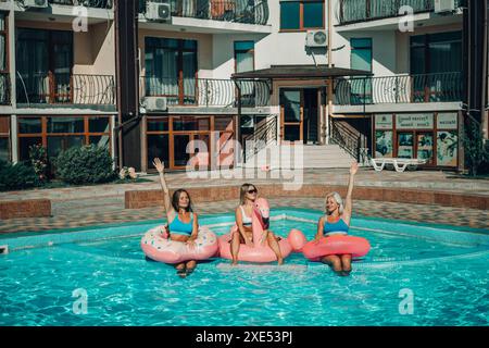 Drei Frauen sitzen auf aufblasbaren Wagen in einem Pool. Die Szene ist unbeschwert und lustig. Stockfoto