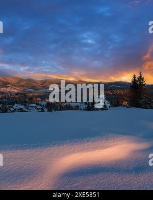 Das Alpendorf ist am Vorabend des Sonnenuntergangs in der Sonne. Im Winter verschneite Hügel und Tannen. Hochauflösendes Nahtbild mit g Stockfoto