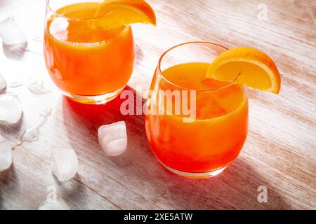 Orangengetränke auf hölzernem Hintergrund, frisch gepresster Saft mit Eis Stockfoto