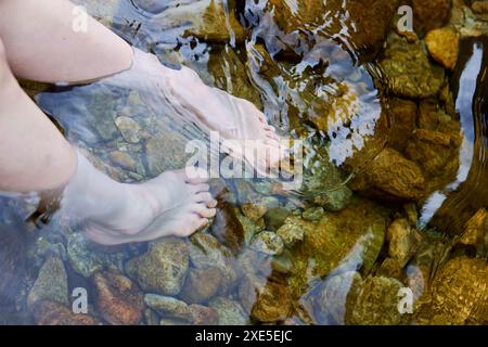 Die Füße der jungen Frau, die im Fluss tränken Stockfoto