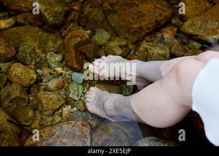 Die Füße der jungen Frau, die im Fluss tränken Stockfoto