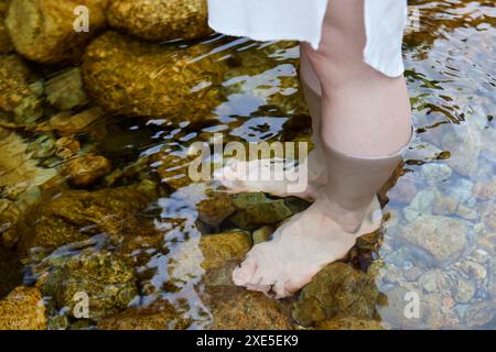 Die Füße der jungen Frau, die im Fluss tränken Stockfoto