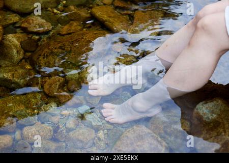 Die Füße der jungen Frau, die im Fluss tränken Stockfoto