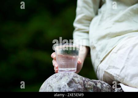 Frau, die ein Glas Wasser in der Natur hält Stockfoto