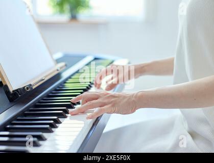 Japanerin spielt Klavier im Wohnzimmer Stockfoto