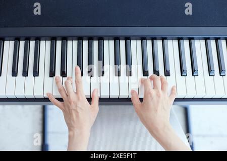 Japanerin spielt Klavier im Wohnzimmer Stockfoto