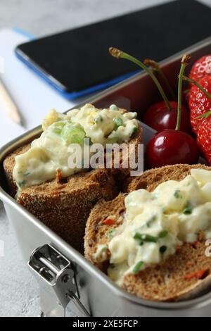 Gesunde Snackpause: Eiersalat Sandwich mit Beeren in Edelstahl Lunchbox Stockfoto