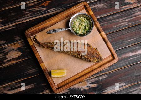 Gebratener Fisch auf Holzbrett mit scharfer Sauce Stockfoto