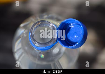 Dresden, Deutschland. Juni 2024. Eine Wasserflasche mit offenem Deckel steht auf einem Tisch. Um Abfall auf dem Land zu reduzieren, werden ab dem 3. Juli 2024 lose Deckel für bestimmte Getränke verboten. Dies gilt für Einwegverpackungen, die ganz oder teilweise aus Kunststoff bestehen - wie Saftkartons oder PET-Einwegflaschen - mit einem Volumen von bis zu drei Litern. Robert Michael/dpa/Alamy Live News Stockfoto