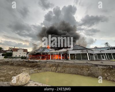 Kempten, Deutschland. Juni 2024. Feuerwehrleute arbeiten daran, ein brennendes Gebäude zu löschen. Nach dem Brand in einem ehemaligen Autohaus im Westen von Kempten schätzt die Polizei den Schaden zunächst auf einstellige Millionenbeträge. Rund 270 Feuerwehrleute, technische Hilfskräfte, Polizei und Rettungsdienste waren am Dienstagabend stundenlang im Einsatz, wie die Polizei am Mittwochabend mitteilte. Die Brandursache blieb zunächst unklar und wurde Gegenstand von Ermittlungen durch die Strafverfolgungsabteilung. Quelle: Markus Dorer/dpa/Alamy Live News Stockfoto