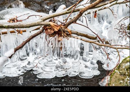 Eisstrukturen am gefrorenen Bach. Eiszapfen am Wasserstrom. Makro, Nahaufnahme, Detail. Stockfoto