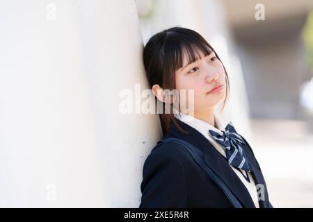 Schulmädchen in Uniform an einer Wand Stockfoto